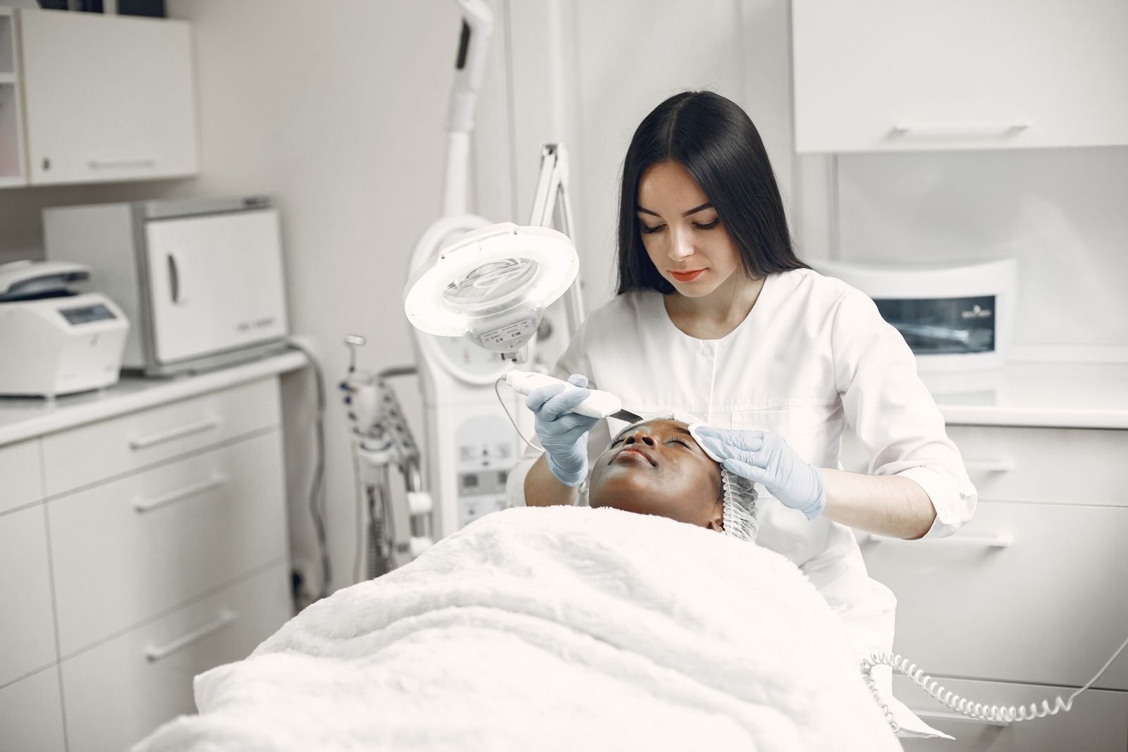 Esteticista aplicando terapia de luz no rosto de uma cliente em consultório